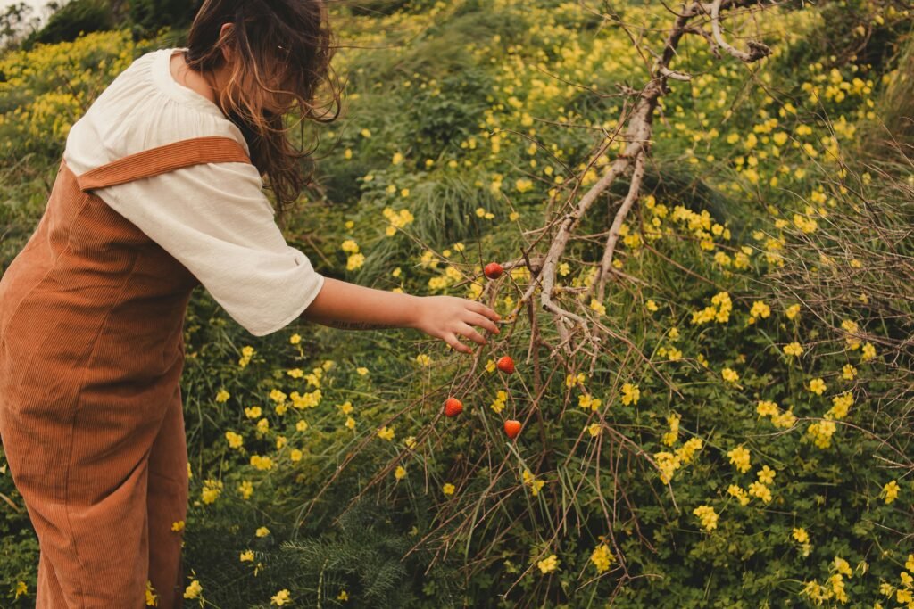 a woman picking berries off of a bush